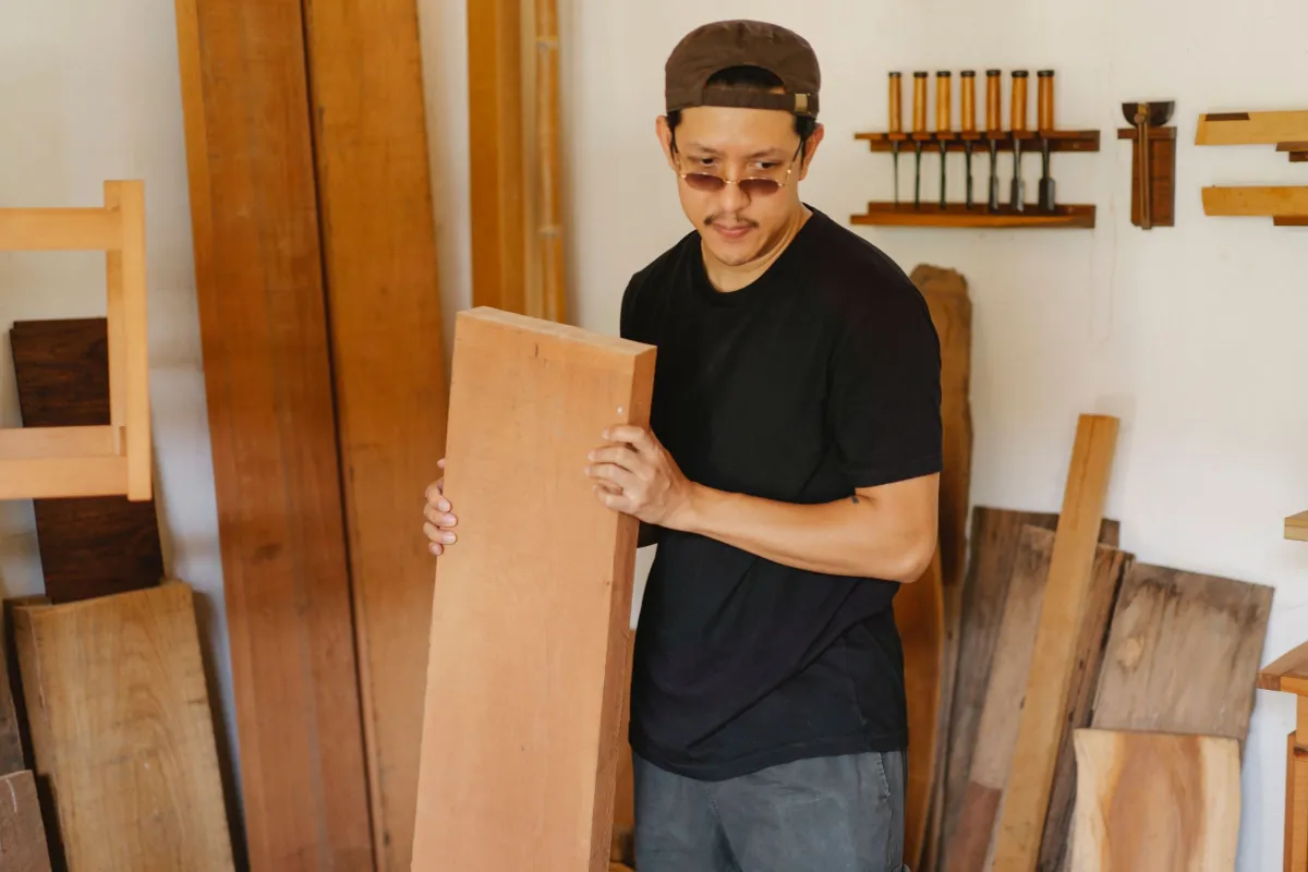 Artisan portant une planche de bois
