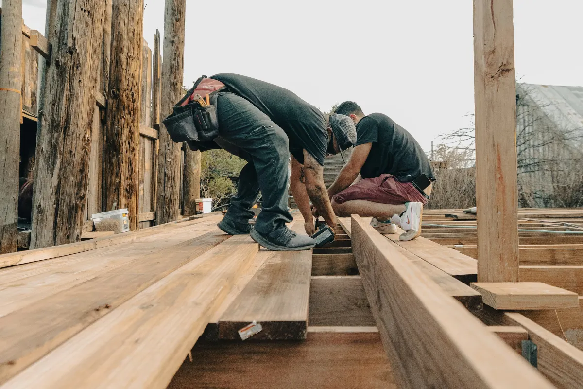 Artisans posant des lames sur l’ossature d’une terrasse