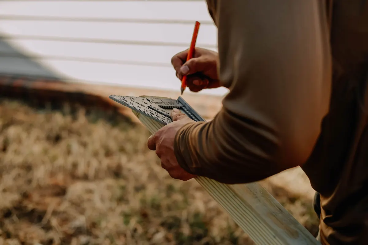 Artisan traçant à l’équerre sur une lame de bois