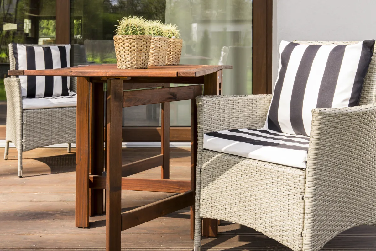 Salon de jardin en rotin et table sur une terrasse en bois