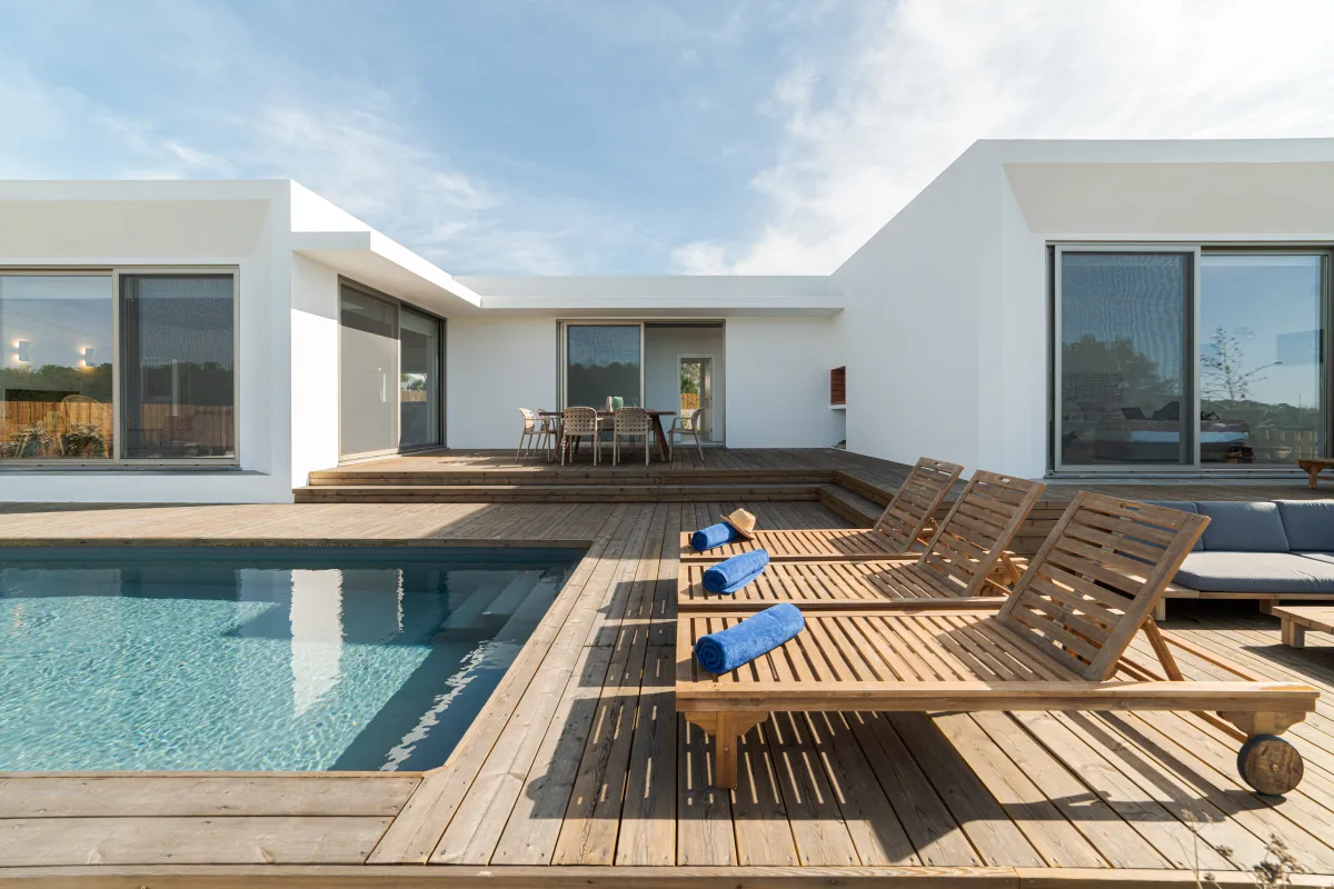 Terrasse en bois clair autour d’une piscine, avec chaises longues